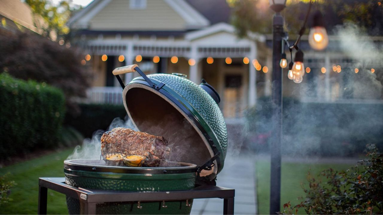 A Big Green Egg Kamado Grill smoking prime rib in a backyard