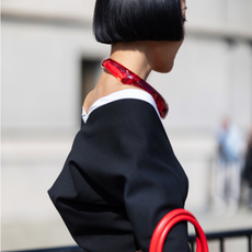Dramatic haircut: bob haircut Kiwi Lee is seen wearing short bob cut hair, a red necklace, a black and white long sleeves top with a red pin,