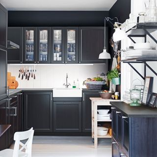 kitchen with black cabinet white flooring and kitchen crockery with vegetables fruits and eggs in basket