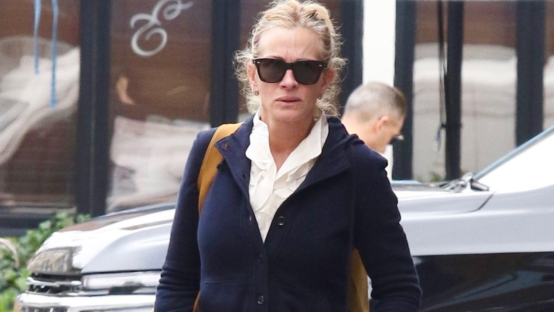 Julia Roberts walks down the street wearing dark-wash jeans with white ballet flats.