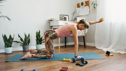 A woman completing a home workout with dumbbells in her living room 