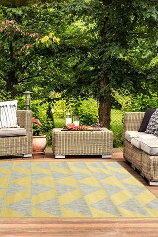 yellow outdoor rug on wooden decking with wicker garden furniture