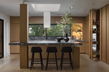 A modern, minimalist kitchen with wooden walls and grey marble countertops