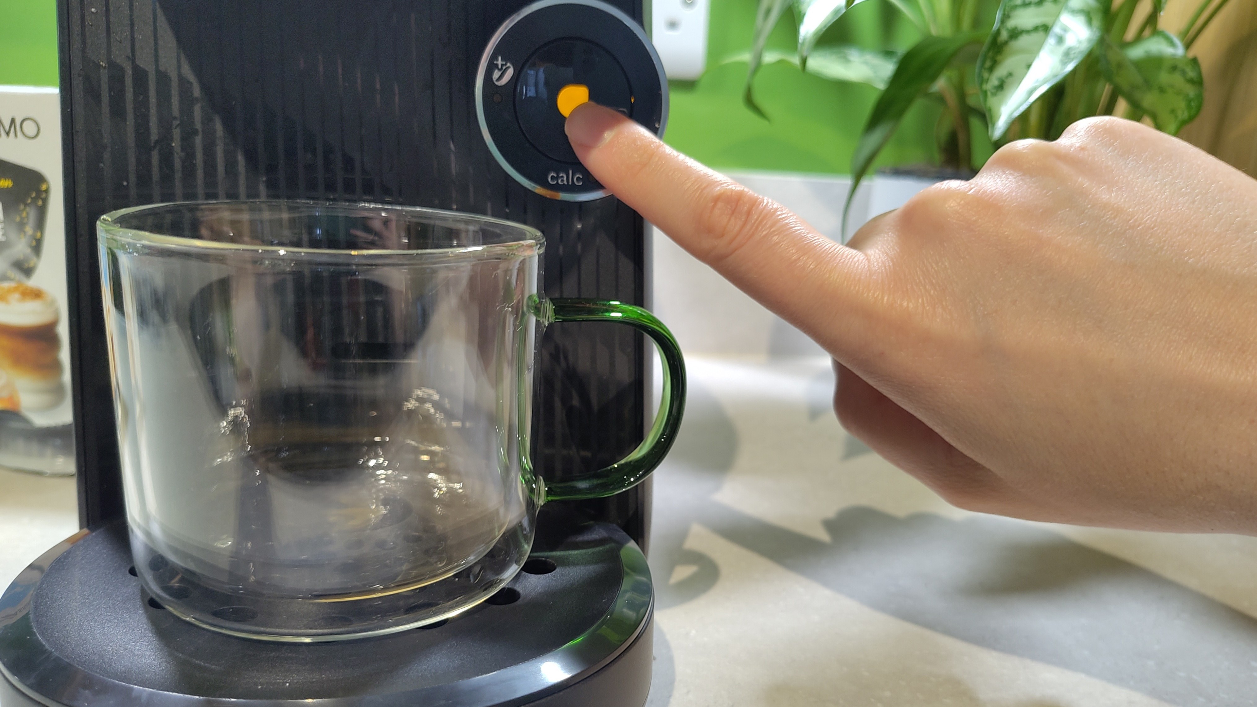 Woman pressing start button on Bosch Tassimo Finesse Friendly coffee maker