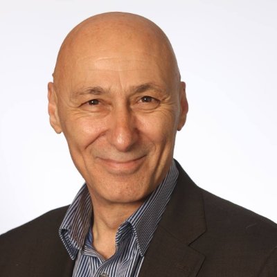 male with bald head wearing brown jacket and blue shirt