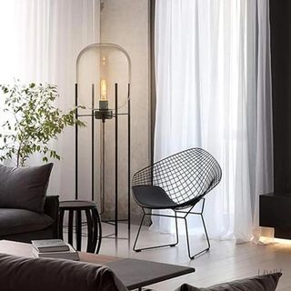 A black floor lamp with an exposed bulb in a moody living room