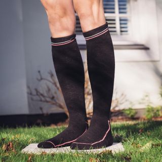 A pair of winter cycling socks stood on a tile in a garden