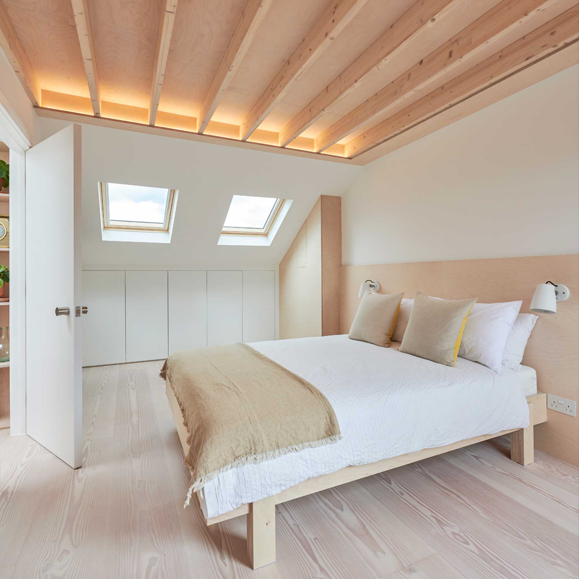 modern loft conversion bedroom with pale wooden flooring