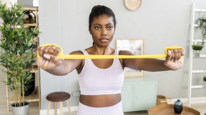 Young woman exercising with resistance band at home