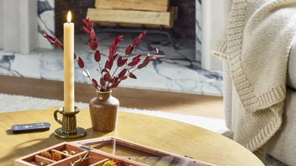 Ribbed Flameless Taper Candles from the Hearth & Hand&trade; with Magnolia collection in a petite glazed ceramic candle holder next to a small neutral vase atop of a circular wooden coffee table