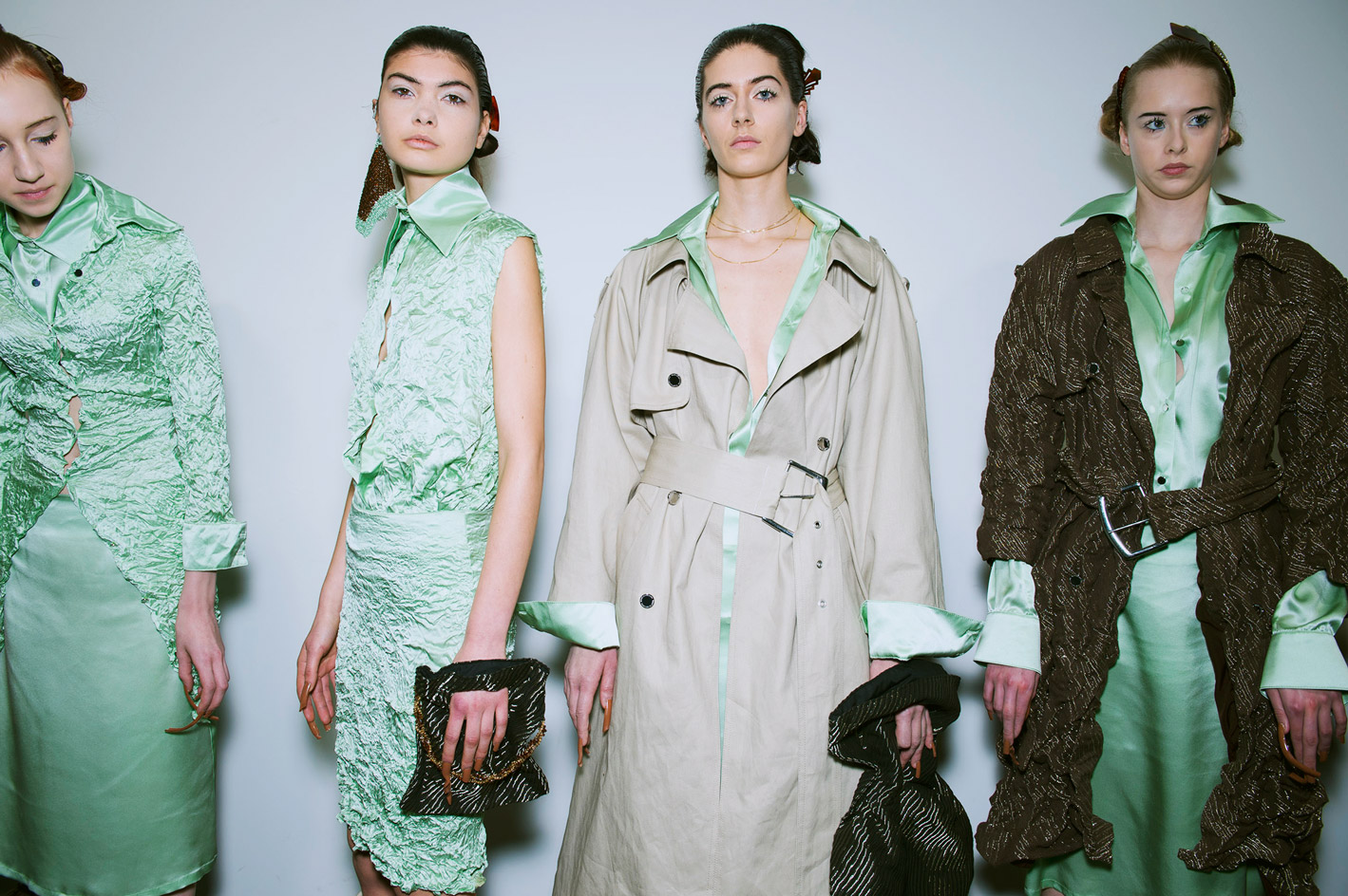Models wear mint green silk dresses and shirts, layered with slouchy outerwear