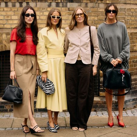 One woman wears red shirt and khaki pants, One model wears a yellow dress. The next woman wears a blazer and black pants, and the last one wears a gray sweater and skirt. 