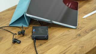 Chord Mojo 2 plugged into iPad and headphones on wooden table