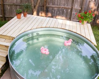 An above ground metal pool with a stepped wood deck