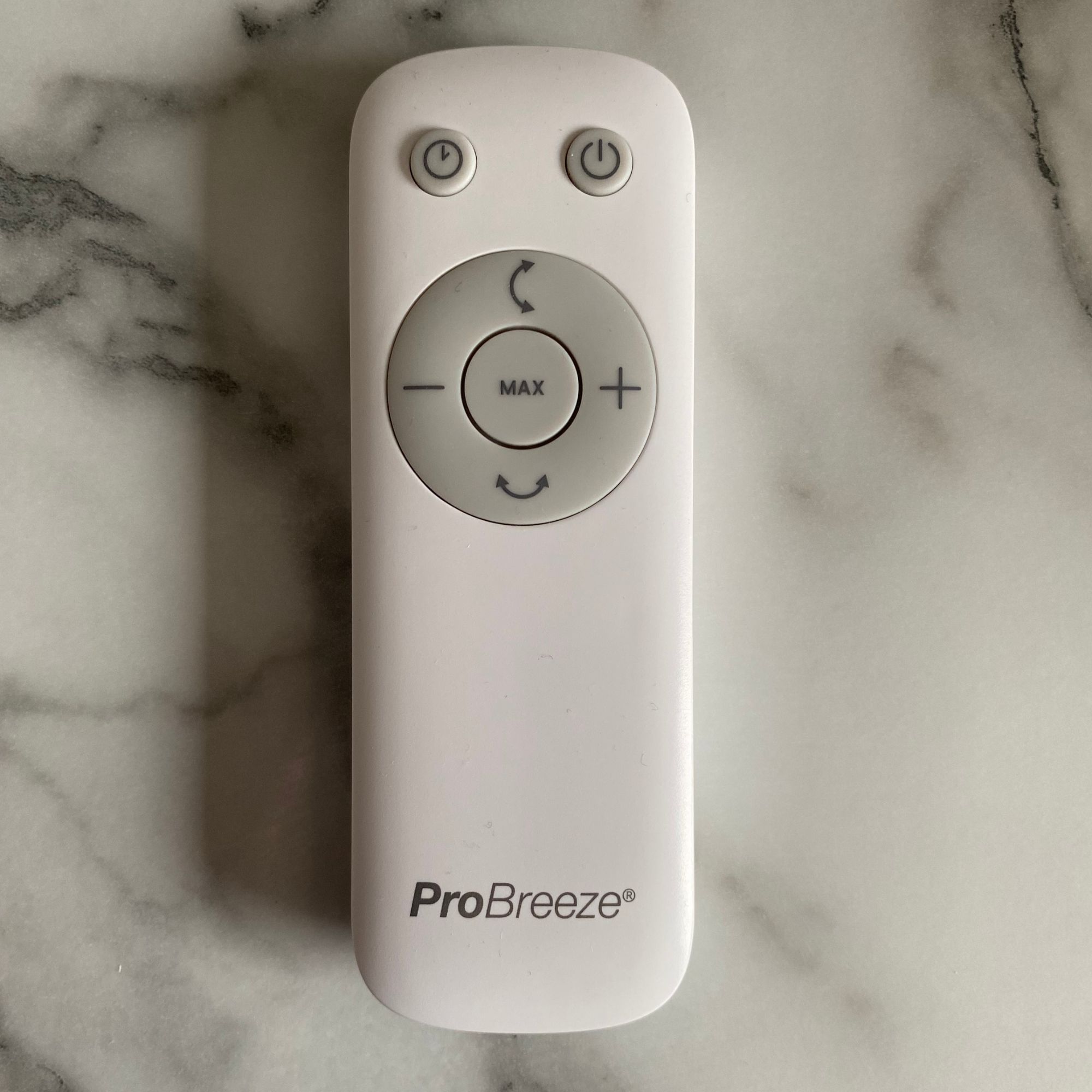 Remote control of the Pro Breeze Airflo 43'' Hybrid Pedestal Fan on a white and grey marble countertop