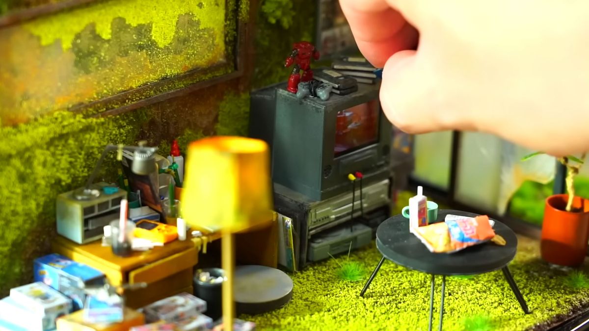 A shot of a small diorama depicting an overgrown living room and a hand in shot