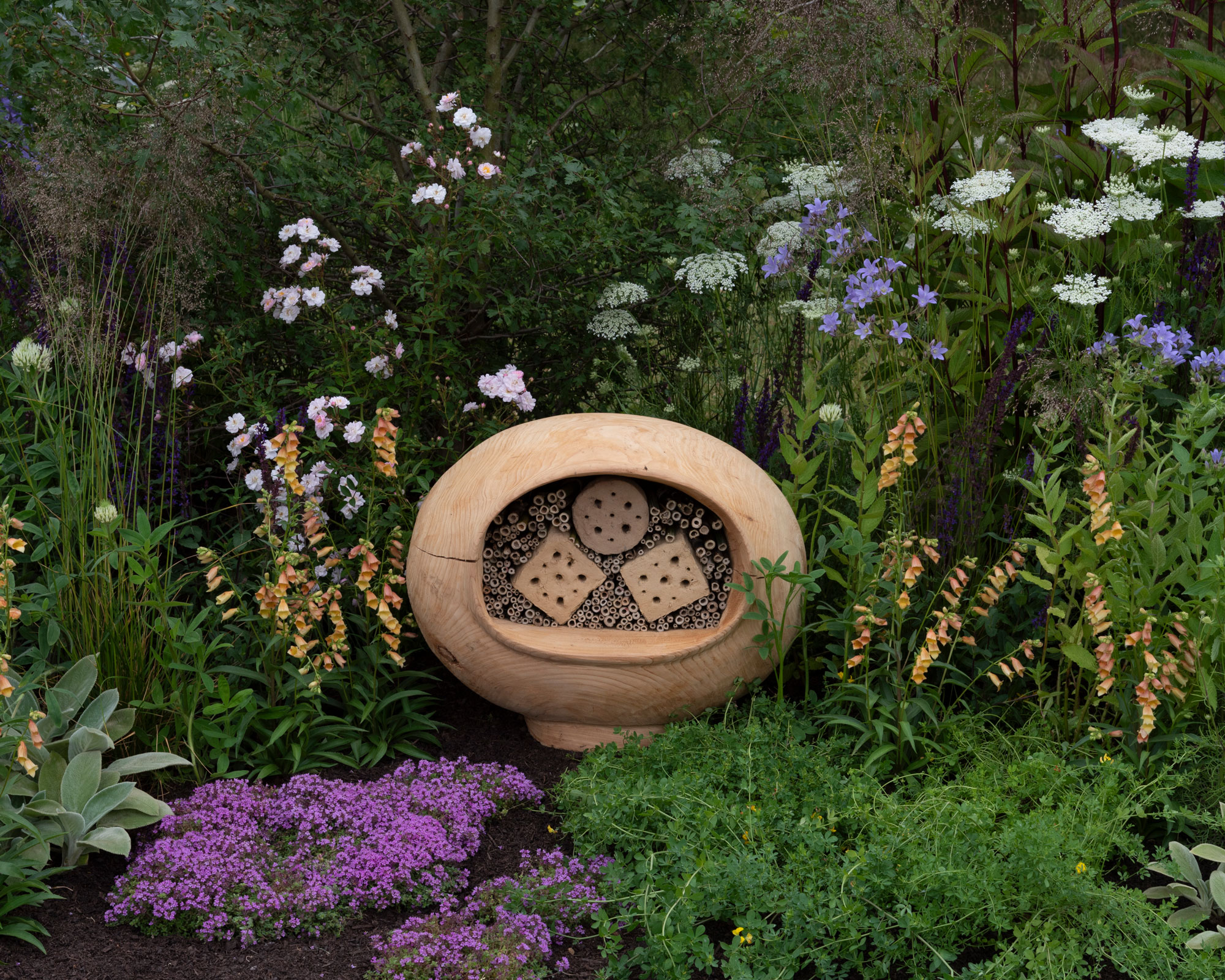 flower border with bug hotel, and planting including salvias, foxgloves and achillea