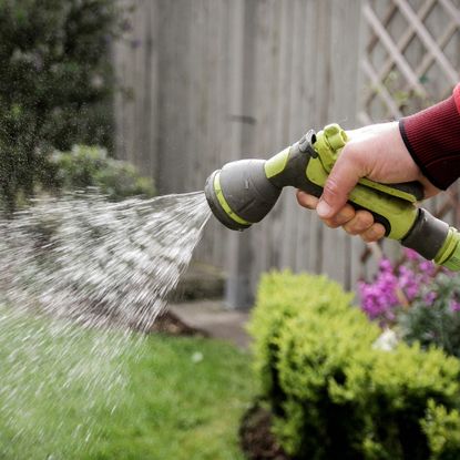 A hand uses a garden hose