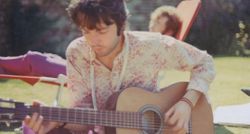 Paul McCartney plays an acoustic guitar in the London sunshine. It's 1967, the summer of love, and you can see John Lennon sunbathing in the background.