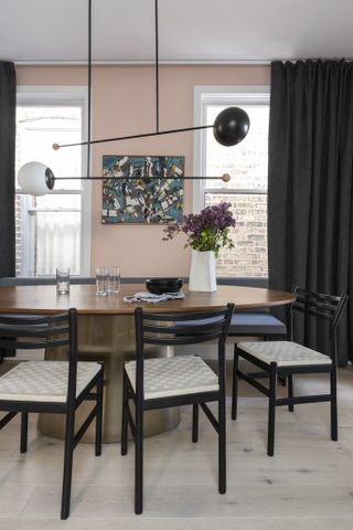pink dining room with black curtains and chairs