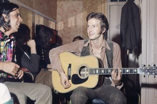 Eric Clapton (right, playing a Martin acoustic guitar) and Bobby Whitlock (left) of Derek and The Dominos, backstage before the band's live debut at the Lyceum Theatre, London, 14th June 1970.