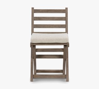 Raylan outdoor teak folding chair in brown with cream seat pad