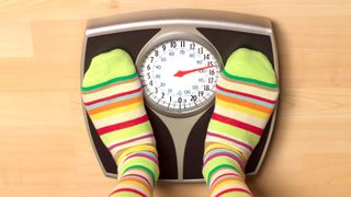 Pair of feet in striped socks standing on bathroom scales