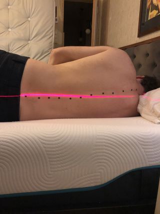 Brook & Wilde posture test – a man lying down on the mattress, with a laser testing his posture