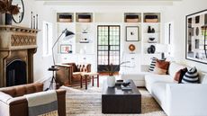 living room storage ideas, white living room with white sectional, tan leather armchair, matching custom storage each side of door, baskets, vases, black floor lamp, black accents