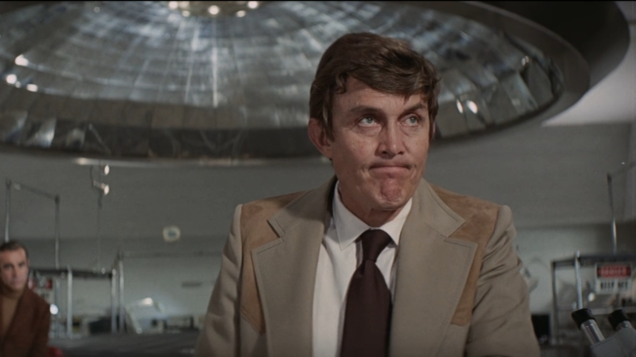 Jimmy Dean stands in the lab looking annoyed in Diamonds Are Forever.