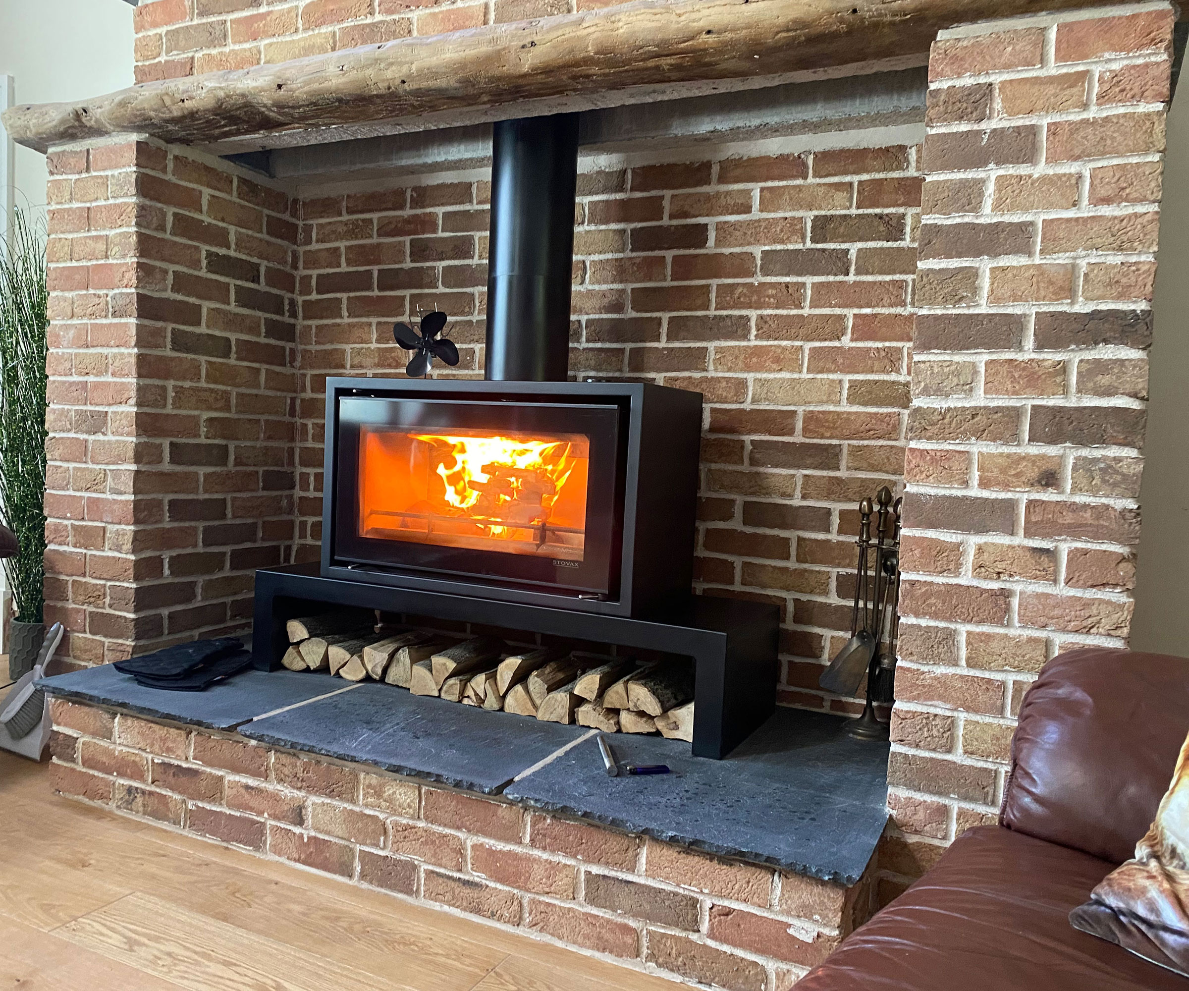 exposed brick inglenook fireplace with log burning stove with slate hearth