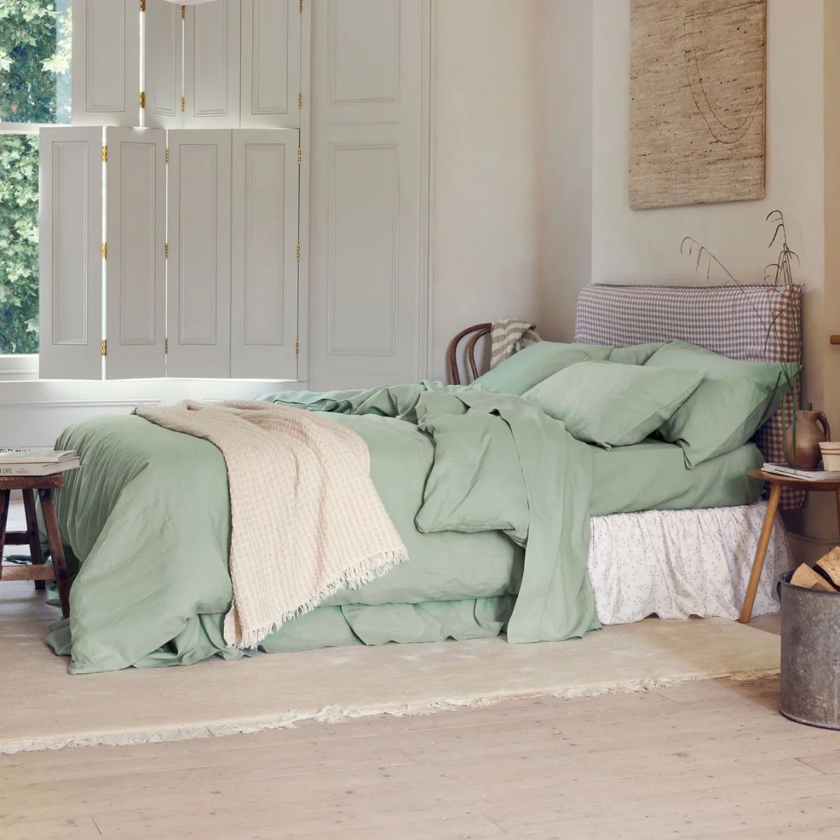 A large bedroom with green linen bedding