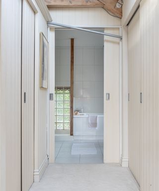 corridor with fitted wardrobes with panelled sliding doors, leading to bathroom