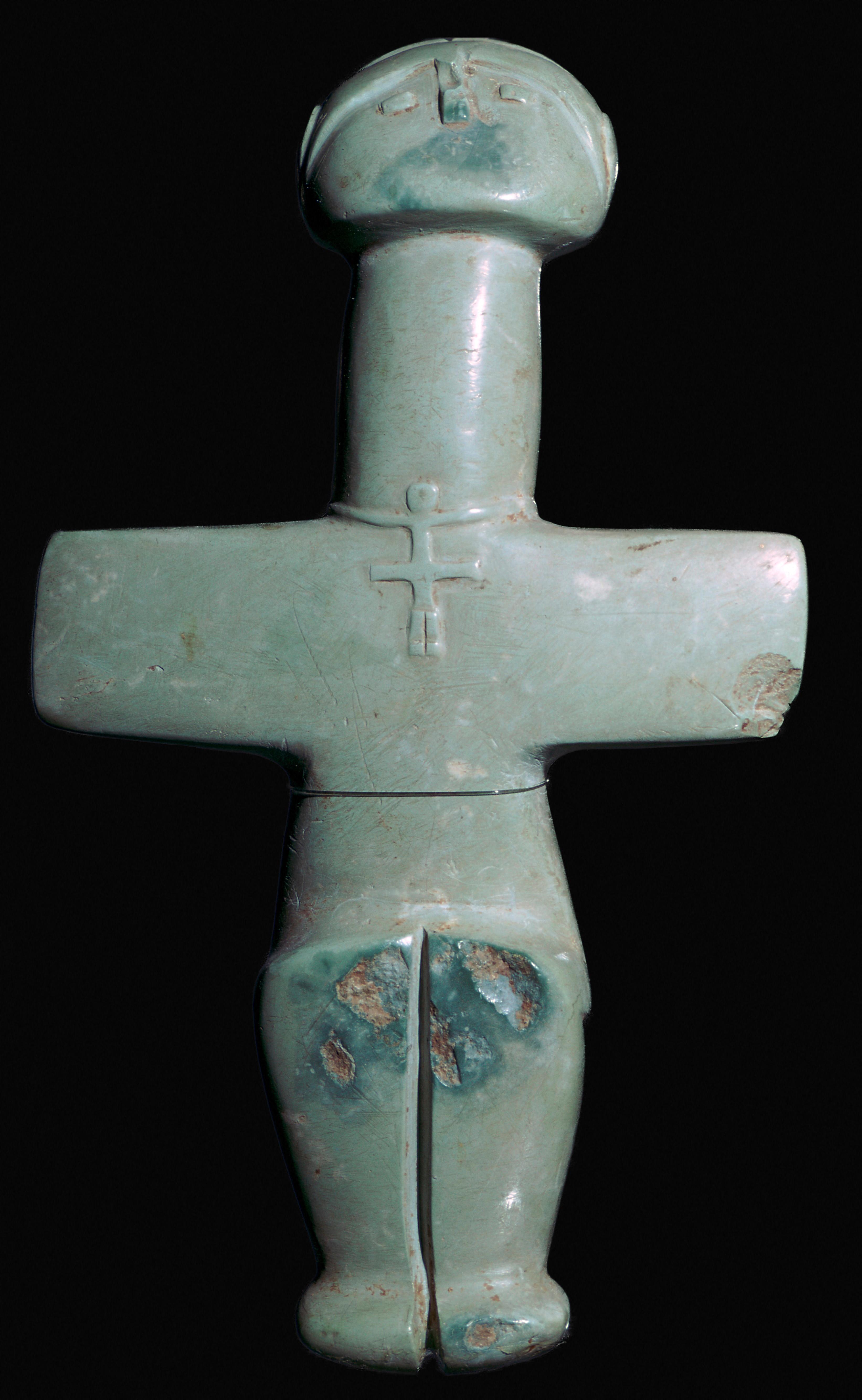 a cross-shaped figurine carved from greenish stone