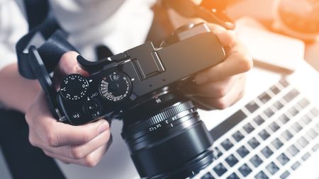 Person checking photos on camera before uploading to laptop