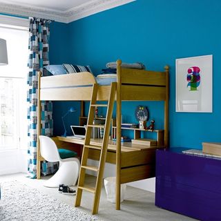 room with blue coloured wall and bunk bed with desk underneath