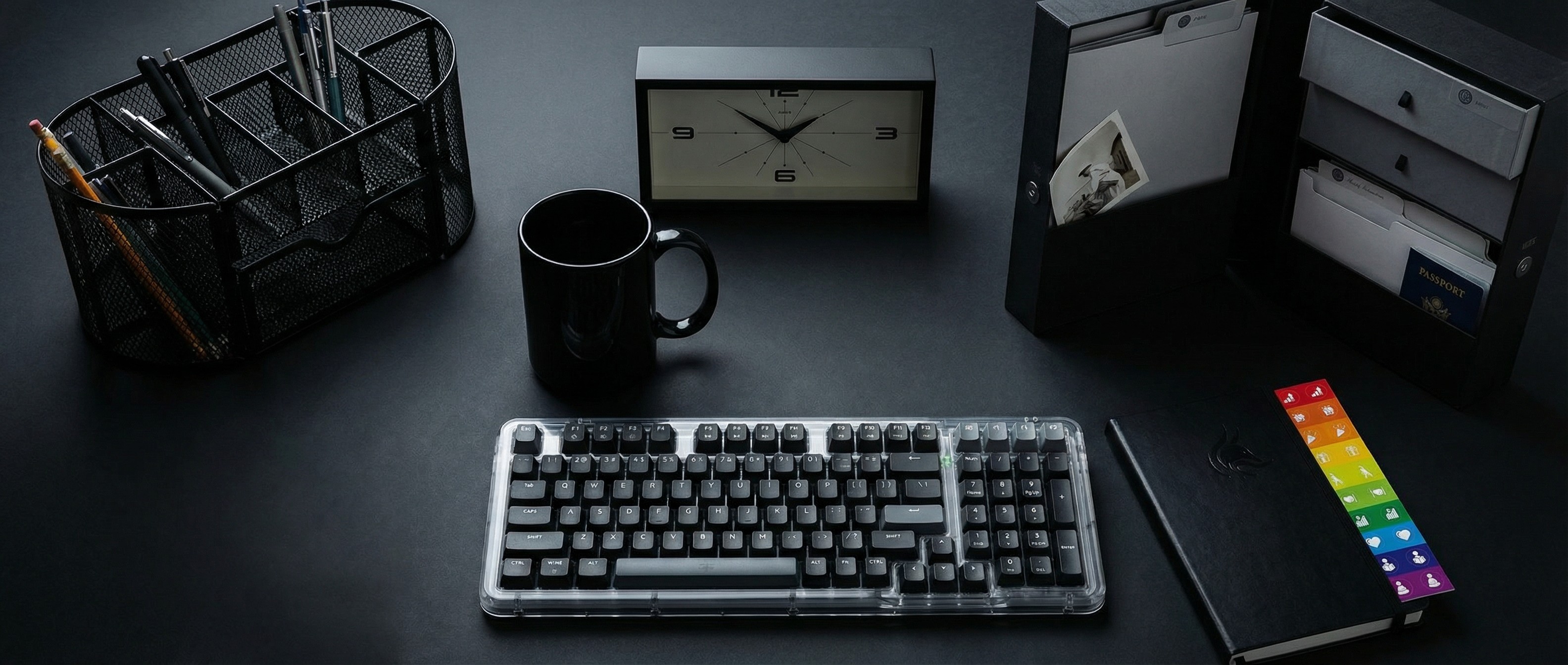 A selection of black-themed home office supplies on a black desk