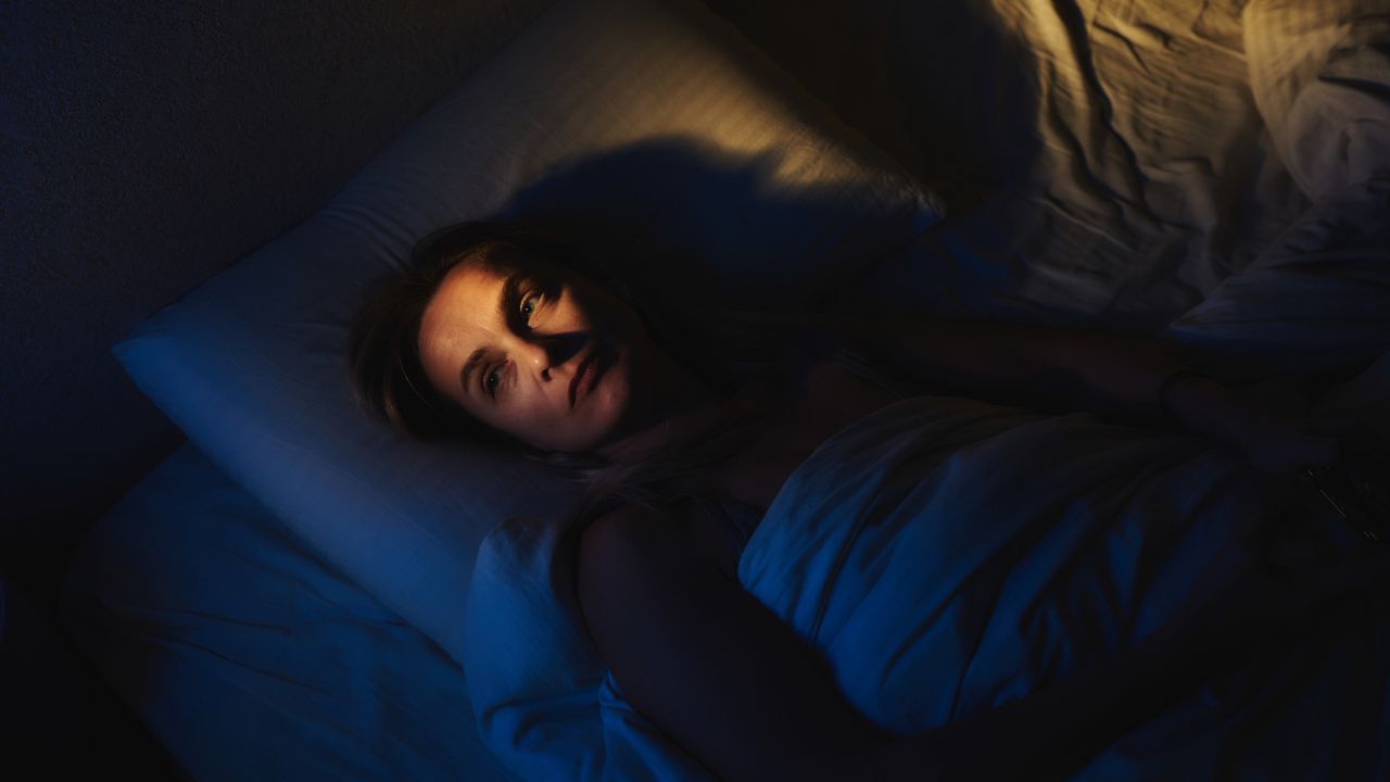 Woman lies in bed awake at night