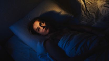 Woman lies in bed awake at night