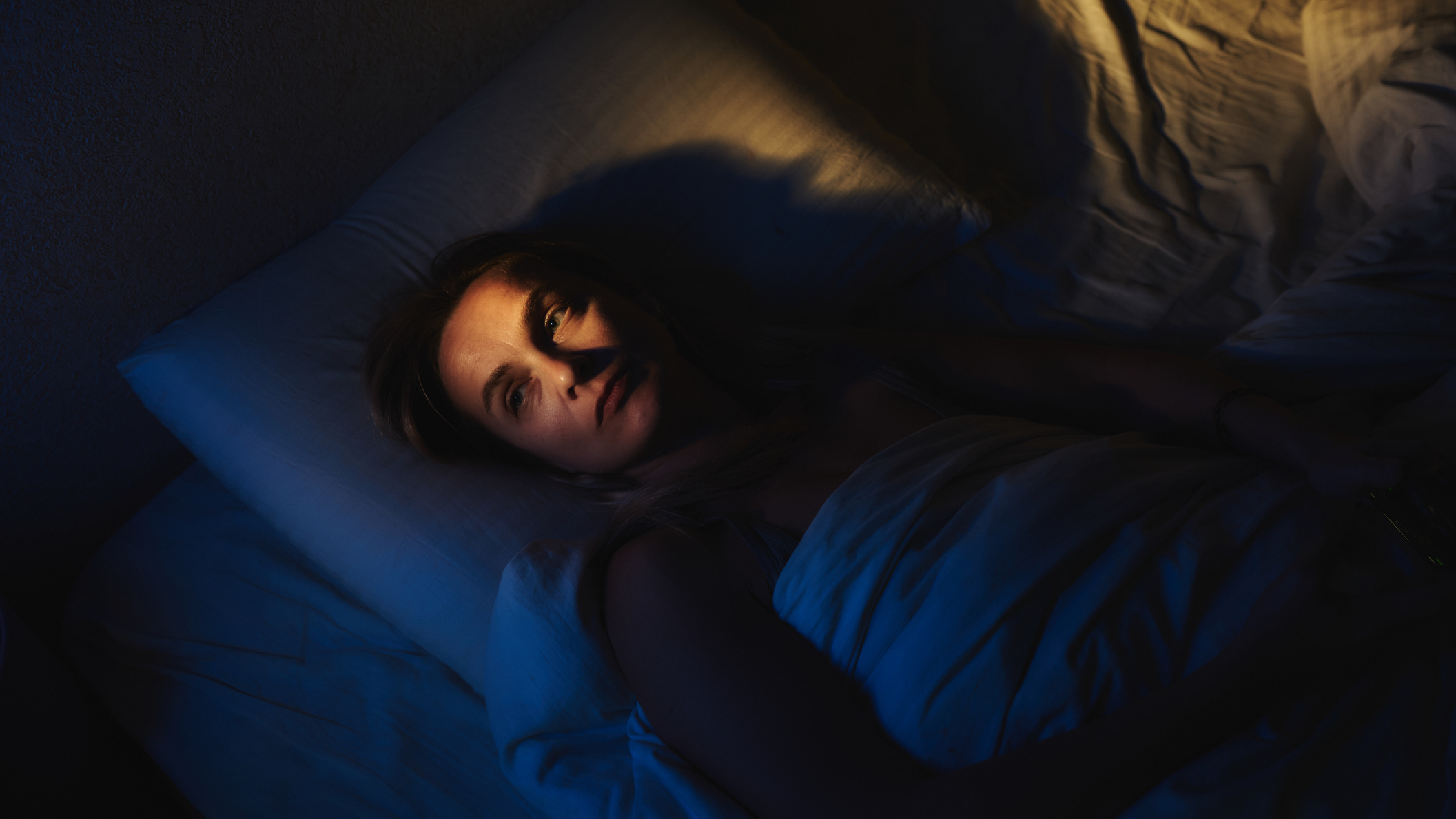 Woman lies in bed awake at night