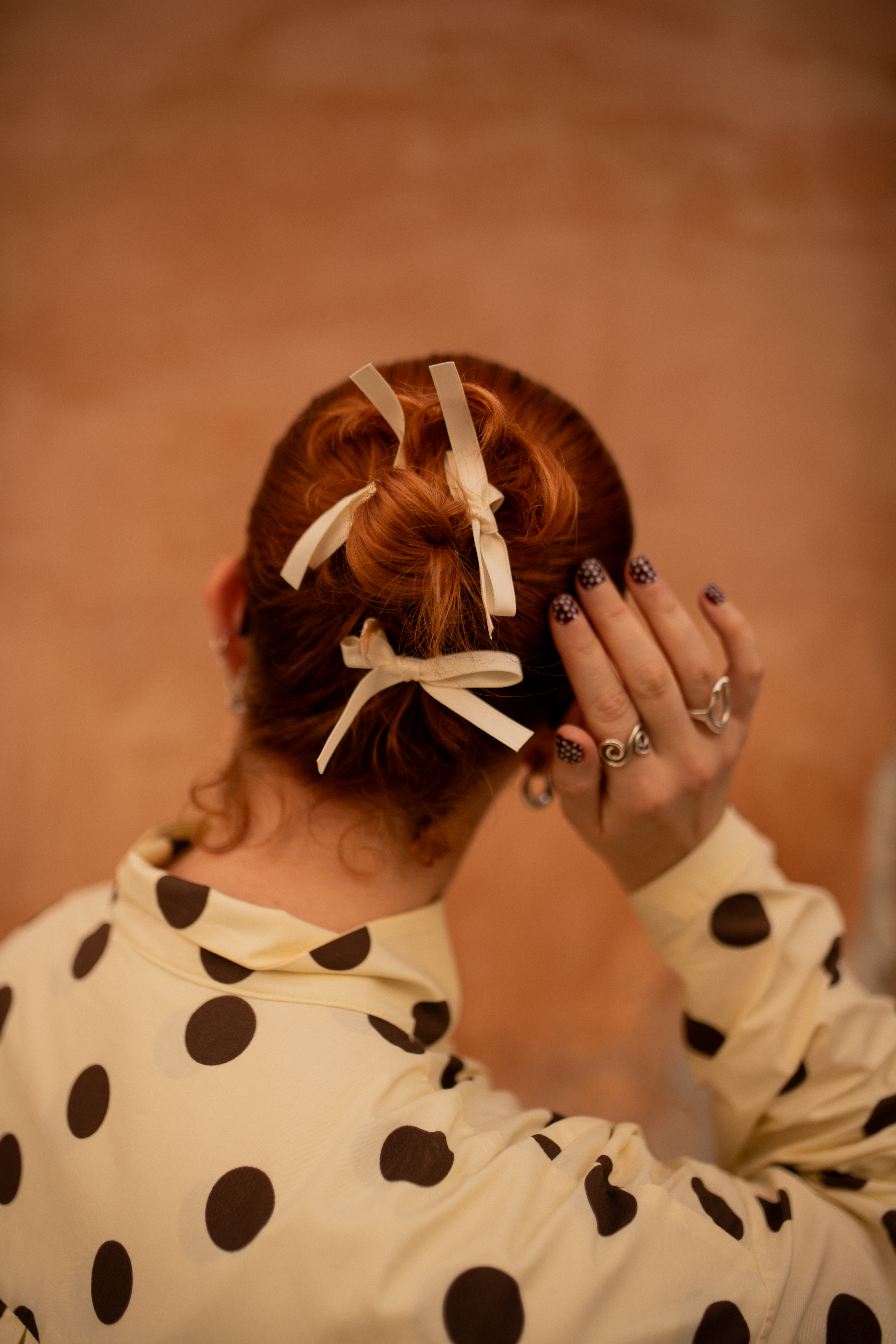 Someone with a bun hairstyle with bows in their hair.