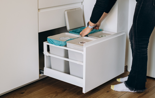 Person bending down and removing a bin from a drawer that contains four bins