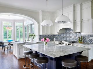 Kitchen with patterned tiles dark granite topped island with bar stools and view to round table in bay window
