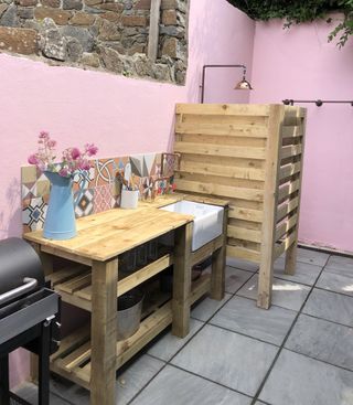 DIY outdoor kitchen and outdoor shower with pink painted garden walls