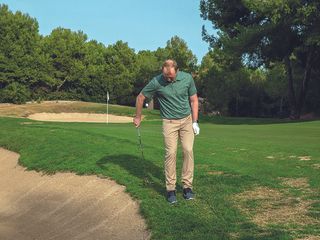 Golf Monthly Top 50 Coach John Howells hitting a one handed shot near the bunker