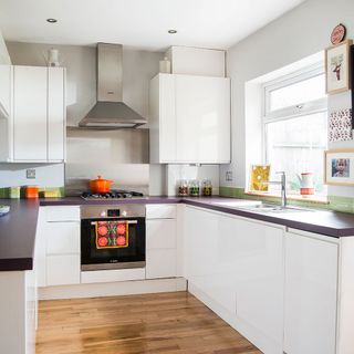 White kitchen with purple counter tops and orange casserole pot on gas stove