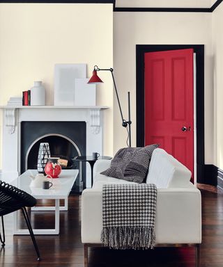 A while living room with black trim and a bright red door