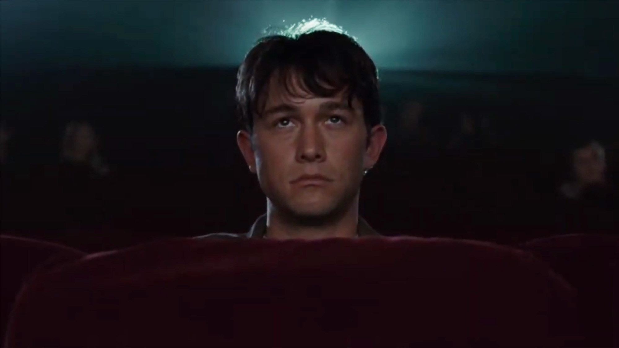 Joseph Gordon-Levitt sits alone in an empty movie theater looking miserable in 500 Days of Summer.