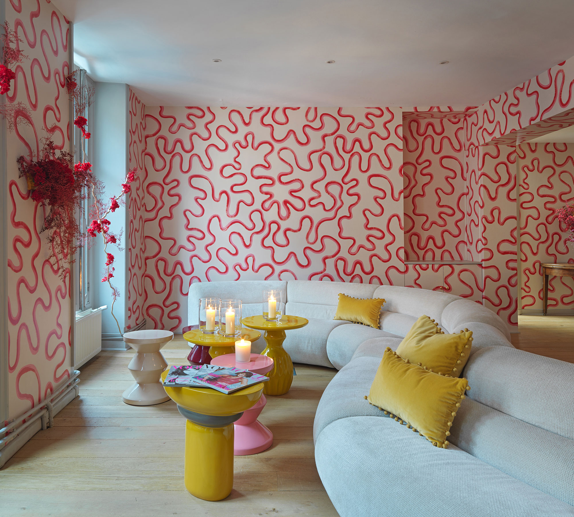 Modern living room with shapely neutral sofa and walls covered in wallpaper with a red and white squiggly pattern