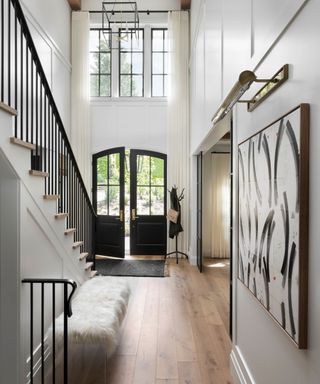 double height entrance hall with door open stairs and white walls and wood floors